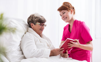 senior woman and caregiver reading a book